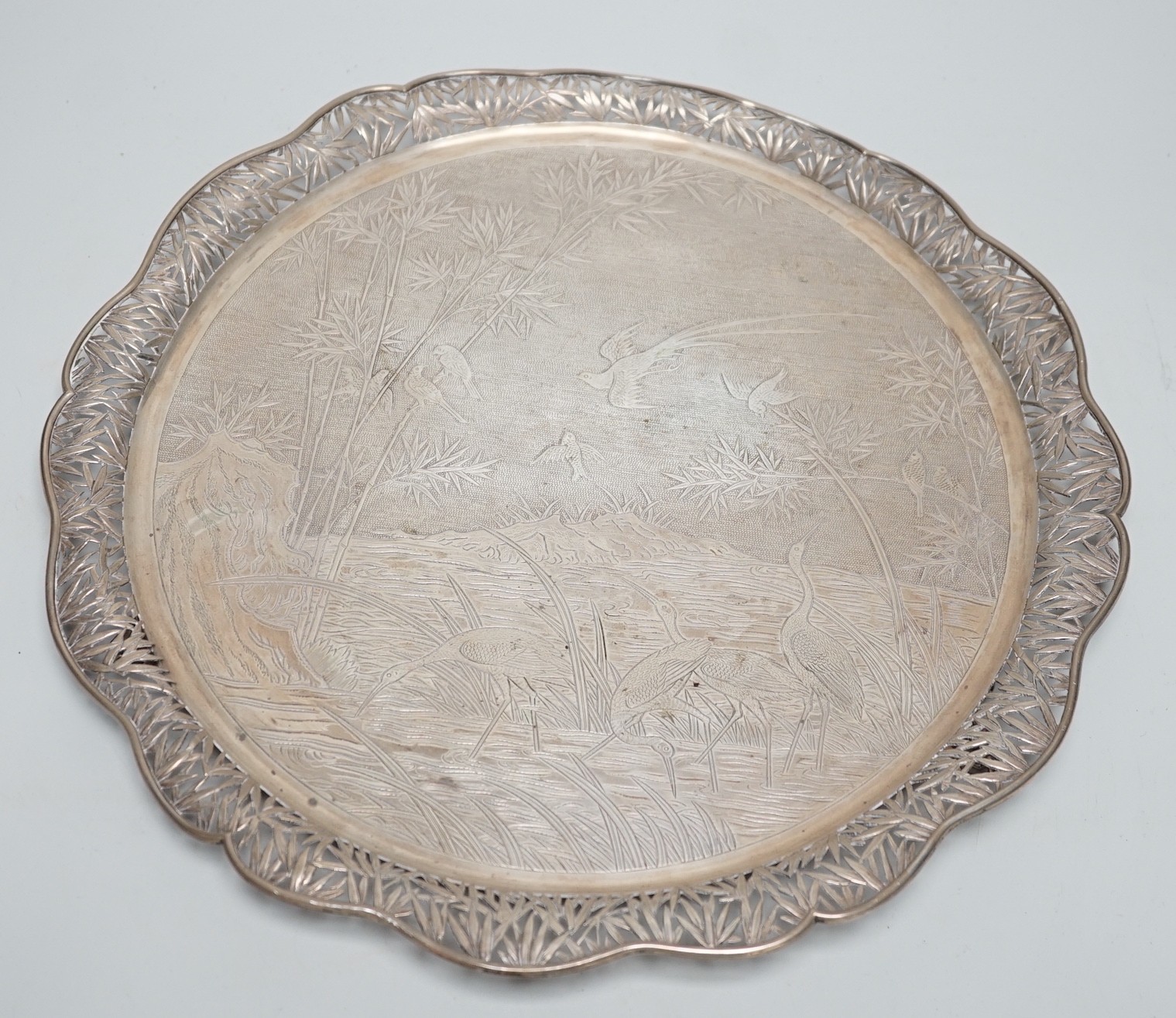 A Chinese Export white metal circular salver with pierced foliate wavy border and engraved with birds amongst reeds and bamboo, maker's mark, WHL, 33.7cm, 36oz.